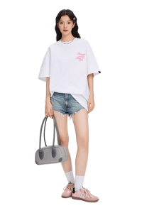 Woman wearing a white blurred rose graphic tee paired with distressed denim shorts and pink sneakers