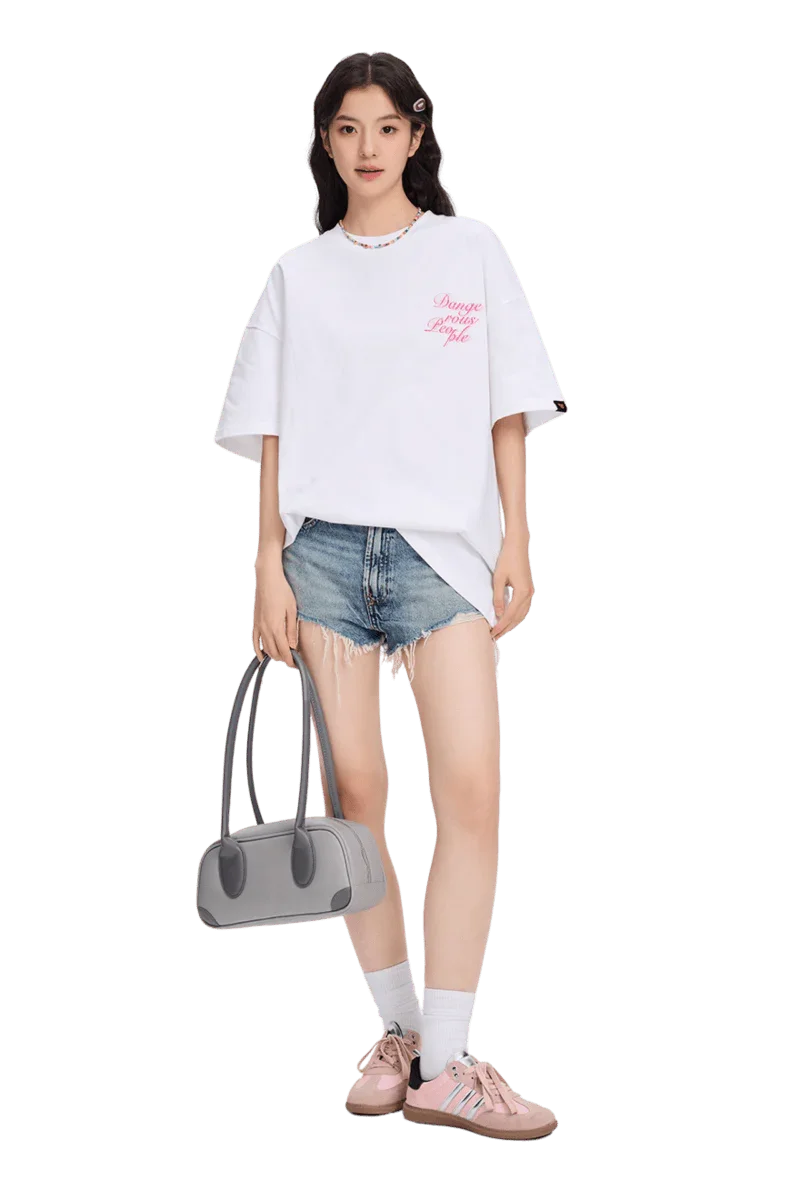 Woman wearing a white blurred rose graphic tee paired with distressed denim shorts and pink sneakers