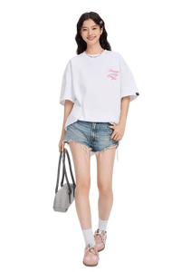 Model wearing a white blurred rose graphic tee paired with distressed denim shorts and pink sneakers