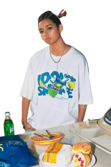 Woman wearing white IDontSmoke Drinks Series Tee with colorful graphic by a table with snacks and drinks
