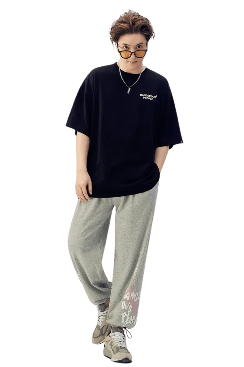 Model wearing Dangerous People graphic tee in black with relaxed fit, paired with gray sweatpants