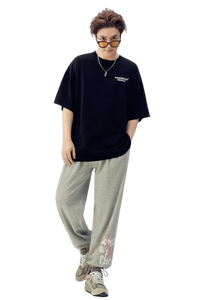 Model wearing Dangerous People graphic tee in black with relaxed fit, paired with gray sweatpants