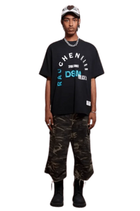 Model wearing IDontSmoke SS25 Arch Logo Tee black graphic t-shirt paired with camo cargo pants and black boots