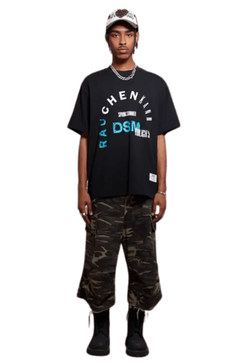 Model wearing IDontSmoke SS25 Arch Logo Tee black graphic t-shirt paired with camo cargo pants and black boots