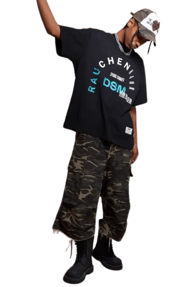 Model wearing IDontSmoke SS25 Arch Logo Tee black graphic t-shirt with camo pants and black boots