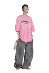 Model wearing Masonprince 2.0 Faded Logo Gradient Tee in pink with oversized gray cargo pants