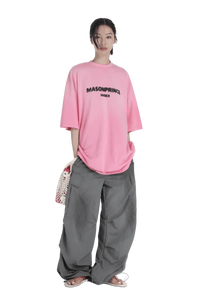 Model wearing Masonprince 2.0 Faded Logo Gradient Tee in pink with oversized gray cargo pants