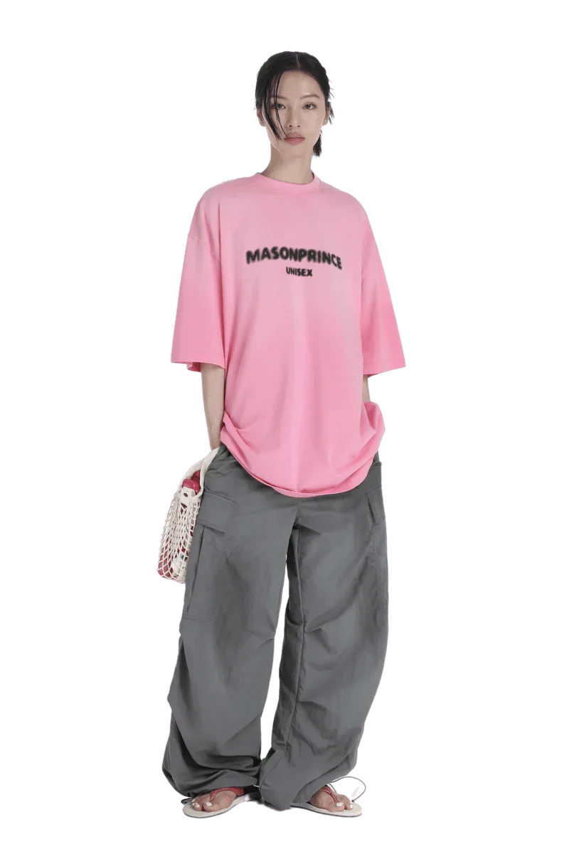 Model wearing Masonprince 2.0 Faded Logo Gradient Tee in pink with oversized gray cargo pants