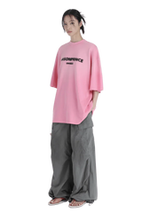Masonprince 2.0 Faded Logo Gradient Tee in pink worn by a model with gray wide-leg pants