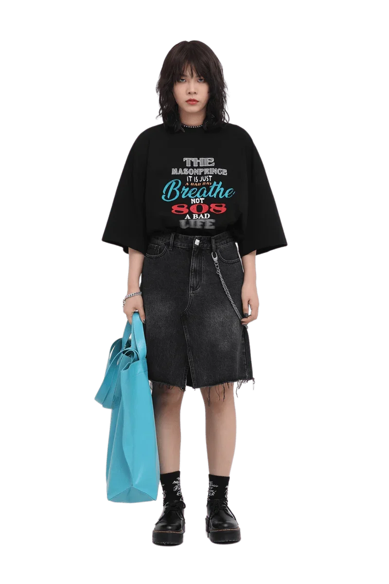 Model wearing black Masonprince 808 Breathe Tee with graphic text paired with black denim skirt and blue tote bag