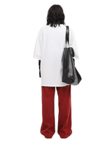 Back view of a person wearing a white Masonprince 808 Breathe Tee with red pants and carrying a black tote bag