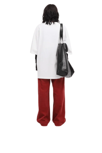 Back view of a person wearing a white Masonprince 808 Breathe Tee with red pants and carrying a black tote bag