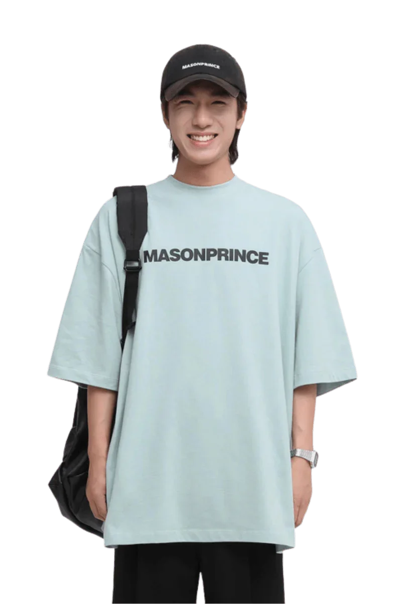 Masonprince Basic Logo Tee in light blue with oversized fit, worn by a smiling model holding a backpack