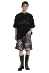 Model wearing black Masonprince Champion League Tee paired with ripped denim shorts and black boots