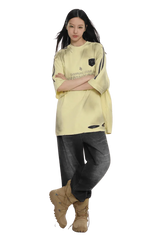 Masonprince Champion League Tee in light yellow worn by model with black pants and beige boots