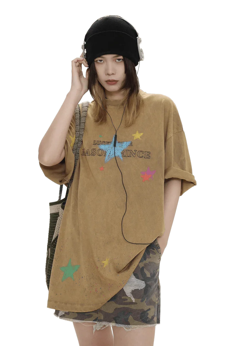 Masonprince colorful star tee worn by model with black beanie and headphones paired with a camo skirt