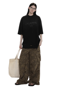Model wearing black Masonprince Gradient Tee oversized fit with camouflage cargo pants and white tote bag