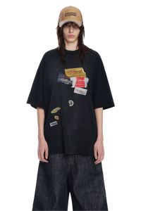 Masonprince patchwork tee in black with multiple colorful fabric patches styled with wide denim pants and a tan cap