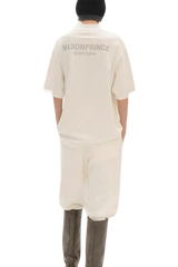 Back view of person wearing Masonprince Spokesman tee in off-white with matching pants and black hat
