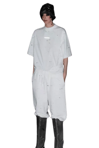 Model wearing white Masonprince Spokesman tee with matching pants and black boots on black background
