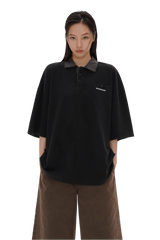 Masonprince SS25 Polo Tee in black with checkered collar worn by model with hands in pockets