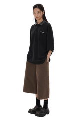 Stylish black Masonprince SS25 Polo Tee with short sleeves worn by a model with brown wide-leg pants