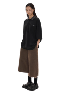 Stylish black Masonprince SS25 Polo Tee with short sleeves worn by a model with brown wide-leg pants
