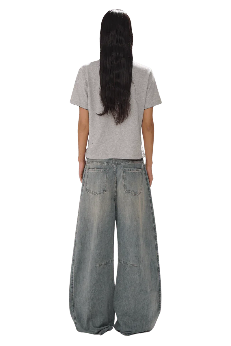 Back view of model wearing Masonprince SS25 Polo Tee in gray with wide leg denim jeans