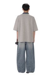 Back view of a person wearing Masonprince SS25 Polo Tee with loose grey short sleeves and blue wide jeans