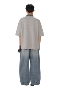 Back view of a person wearing Masonprince SS25 Polo Tee with loose grey short sleeves and blue wide jeans