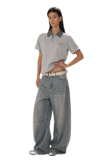 Model wearing Masonprince SS25 Polo Tee in gray with contrast collar paired with wide-leg jeans