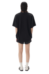 Back view of a model wearing Masonprince SS25 Tape Tee black oversized t-shirt with shorts and sandals