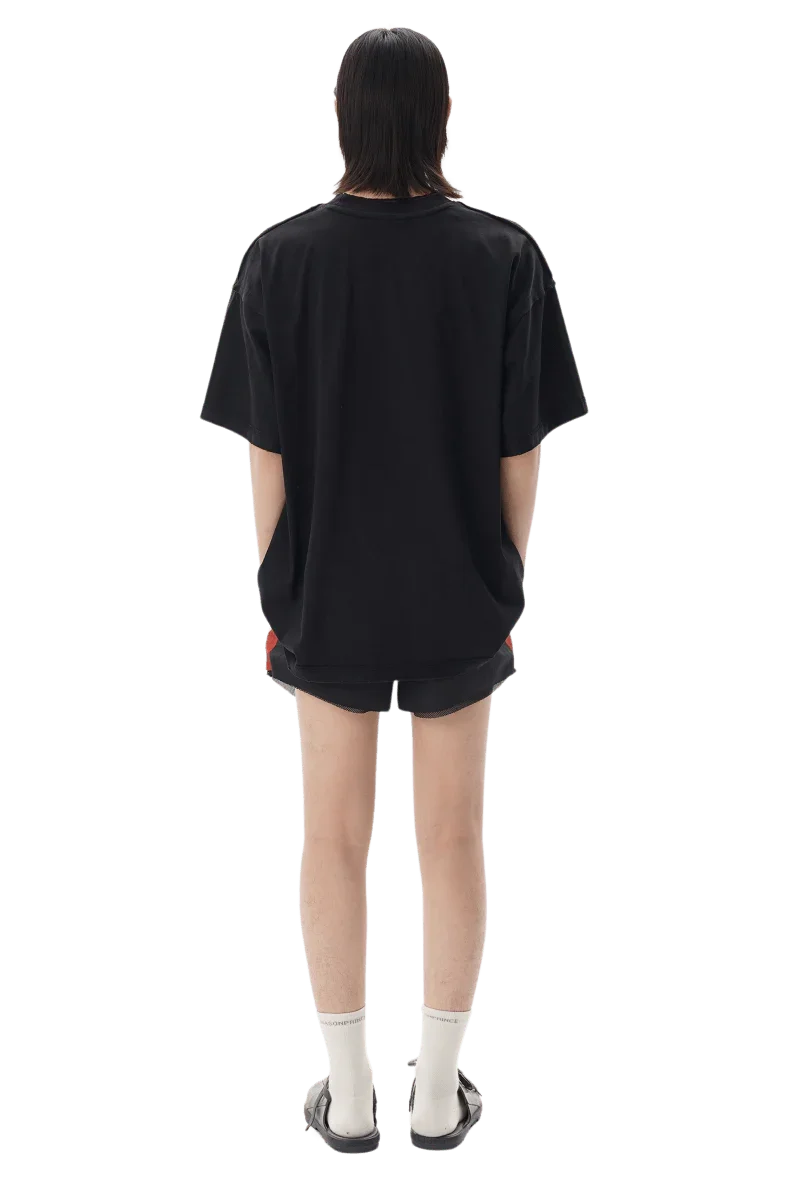 Back view of a model wearing Masonprince SS25 Tape Tee black oversized t-shirt with shorts and sandals