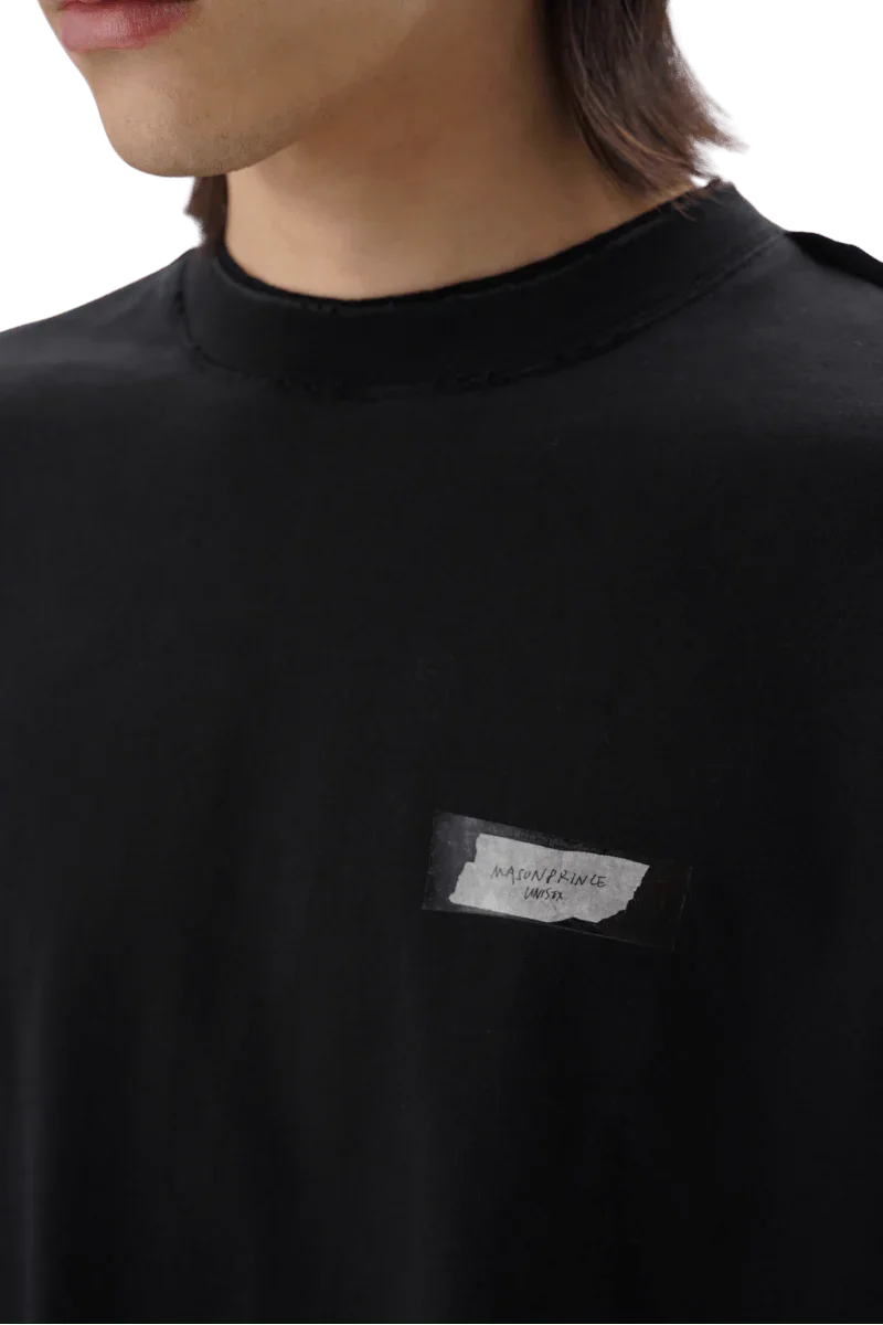 Close-up of black Masonprince SS25 Tape Tee with small white label on chest worn by model