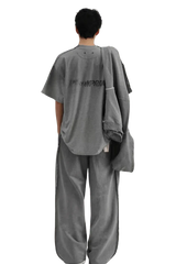 Back view of a person wearing a gray Masonprince Tag Drop Tee with matching wide-leg pants and jacket
