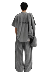 Back view of a person wearing a gray Masonprince Tag Drop Tee with matching wide-leg pants and jacket