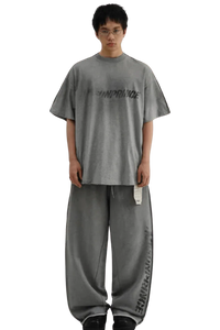 Model wearing gray Masonprince Tag Drop Tee with matching loose pants on black background