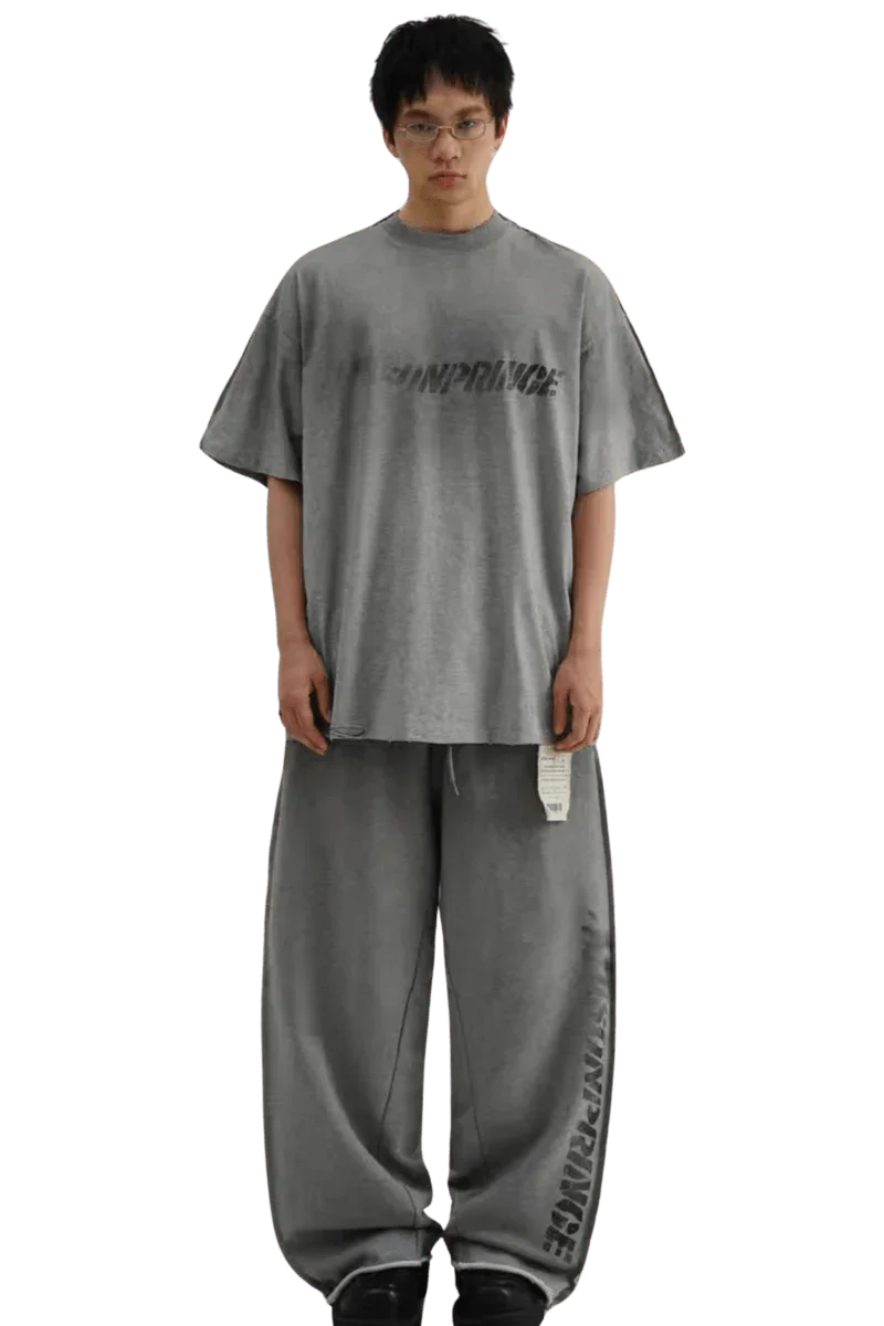 Model wearing gray Masonprince Tag Drop Tee with matching loose pants on black background