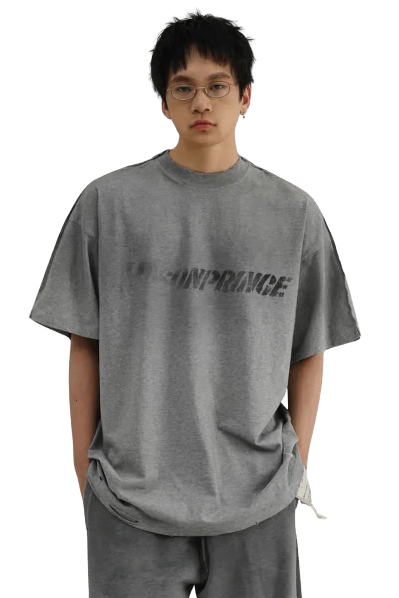 Masonprince Tag Drop Tee in gray worn by model with glasses featuring bold logo print on front