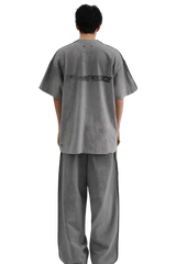Back view of a person wearing Masonprince Tag Drop Tee in gray with matching wide-leg pants