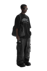 Man wearing Masonprince black unisex logo tee with oversized fit and carrying a black bag