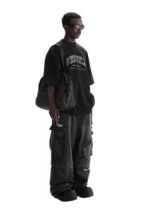 Man wearing Masonprince black unisex logo tee with oversized fit and carrying a black bag