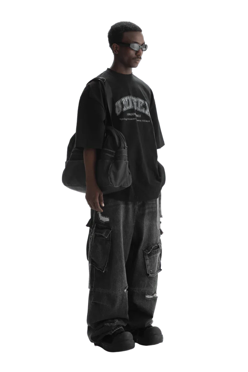 Man wearing Masonprince black unisex logo tee with oversized fit and carrying a black bag