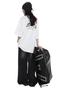 Masonprince unisex logo tee worn by model with black beanie and wide black pants holding large black bag