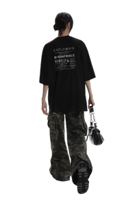 Back view of a person wearing black Masonprince WashTag Tee with white print and camo pants