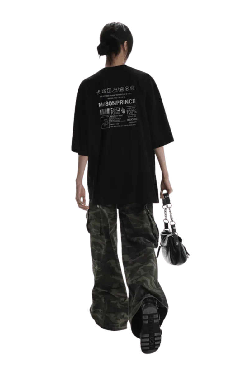 Back view of a person wearing black Masonprince WashTag Tee with white print and camo pants