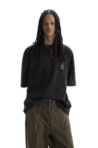 Model wearing black Masonprince WashTag Tee with relaxed fit and olive green pants on black background