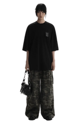 Masonprince WashTag Tee black oversized T-shirt with small chest tag worn with camo pants