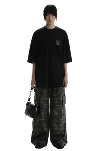 Masonprince WashTag Tee black oversized T-shirt with small chest tag worn with camo pants