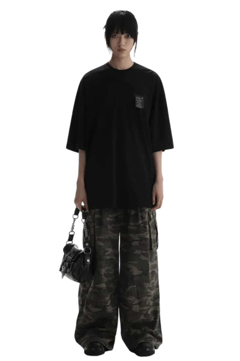 Masonprince WashTag Tee black oversized T-shirt with small chest tag worn with camo pants